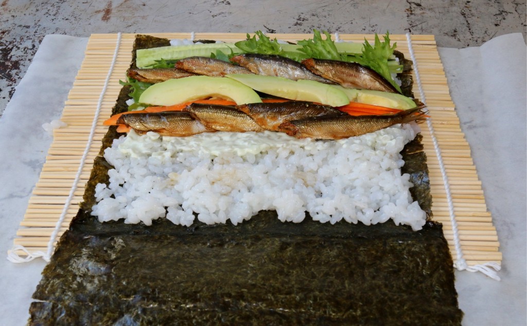 Sushiburrito täytettynä, käärimistä vaille valmis. Sushimatto helpottaa käärimistä, mutta se onnistuu voipaperinkin avulla.