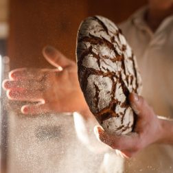 Leipuri taputtelee vasta paistetusta leivästä jauhoja pois.