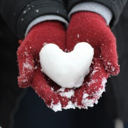 Käsissä lumesta tehty sydän.